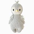 A cuddle and kind doll from the baby animal collection, baby penguin, shown from the front. Baby penguin is grey with fluffy wings and a tuft of feathers on its head.