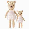 Olivia the honey bear in the regular and little sizes, shown from the front. Olivia is wearing a lavender apron dress and a daisy chain flower crown.