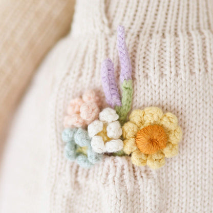 A close-up showing the hand-knit details of Goldie the honey bear's flower bouquet.