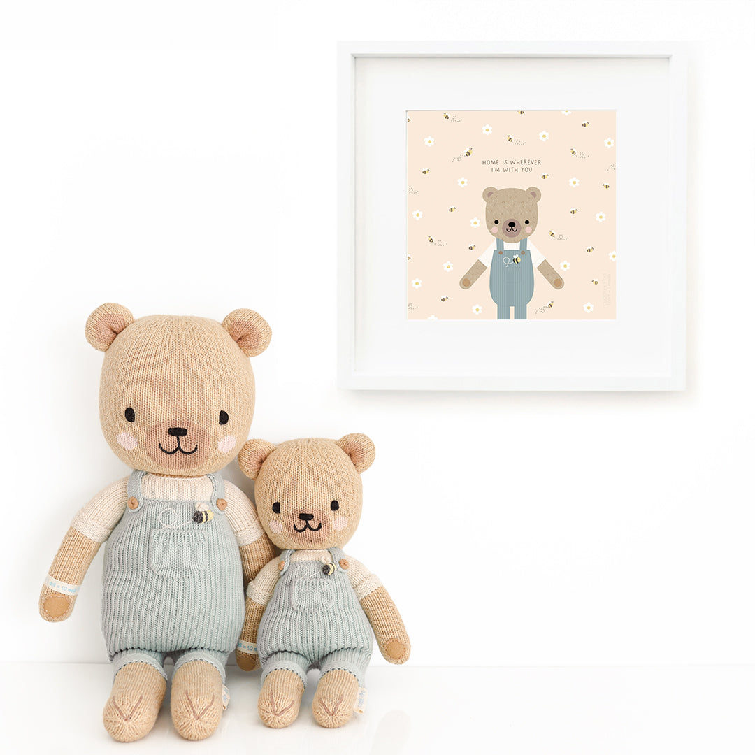 Two Charlie the honey bear stuffed dolls sitting beside a framed print with a picture of Charlie, with text that says "Home is wherever I’m with you."