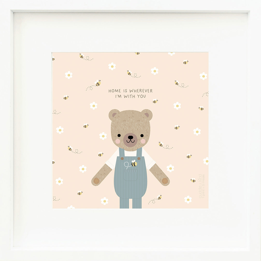 An inspirational print with a graphic of Charlie the honey bear on a blush background with a bumblebee print and the words “Home is wherever I’m with you” in black, whimsical font.