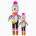 Aspen the penguin in the regular and little sizes, shown from the front. Aspen is wearing a striped pink, yellow, gray, and white scarf, a grey hat with a pink pompom and brown and pink boots.