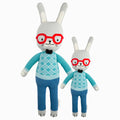 Benedict the bunny in the regular and little sizes, shown from the front. Benedict is wearing red glasses, a blue sweater with a bow tie, and blue pants.