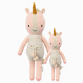 Ella the unicorn in the regular and little sizes, shown from the front. Ella is wearing a white romper with confetti polka dots and a pom-pom tie.