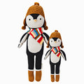 Everest the penguin in the regular and little sizes, shown from the front. Everest is wearing a striped red, yellow, gray, blue and brown scarf, with a brown hat and brown boots.