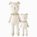 Lucas the llama in the regular and little sizes, shown from the front. Lucas has blue tassels hanging on his fuzzy ears and a necklace of grey, yellow and blue tassels around his neck.