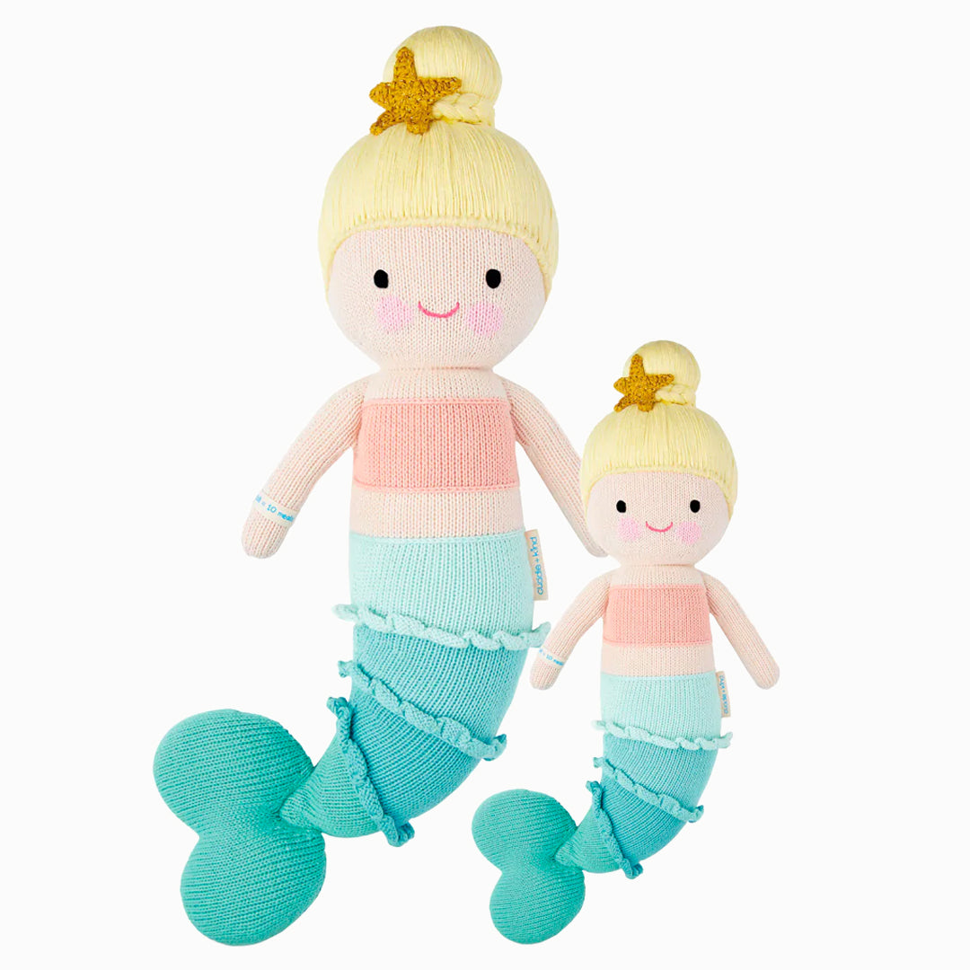 Skye the mermaid in the regular and little sizes, shown from the front. Skye has blond hair in a bun, with a star ornament on top. She has a pink top and her tail is blue with ruffled details.