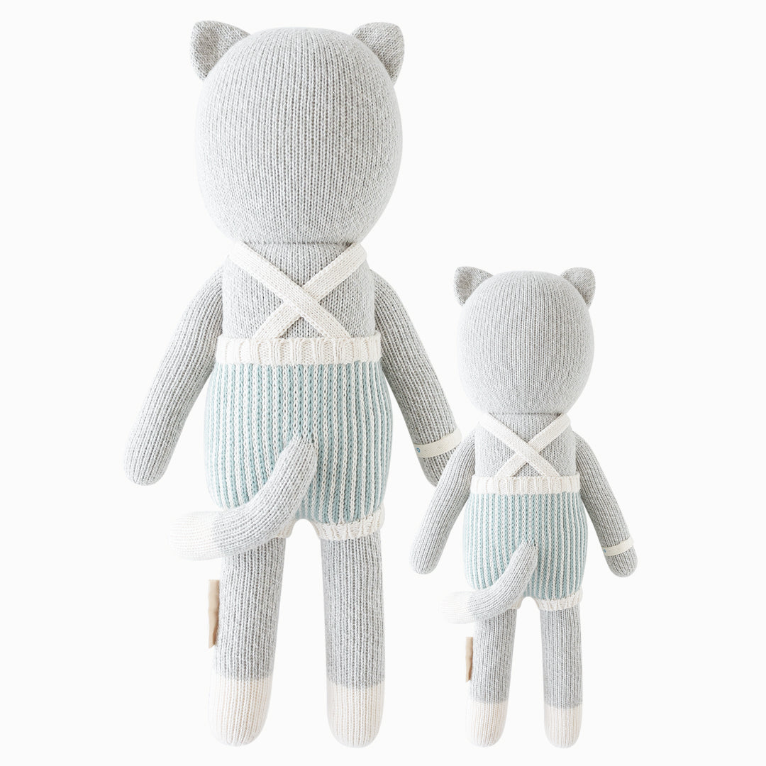 Cuddle and kind doll Dylan the kitten in the regular and little sizes, shown from the back. Dylan’s tail is poking out the back of his romper, and the straps of his romper are criss-crossed.