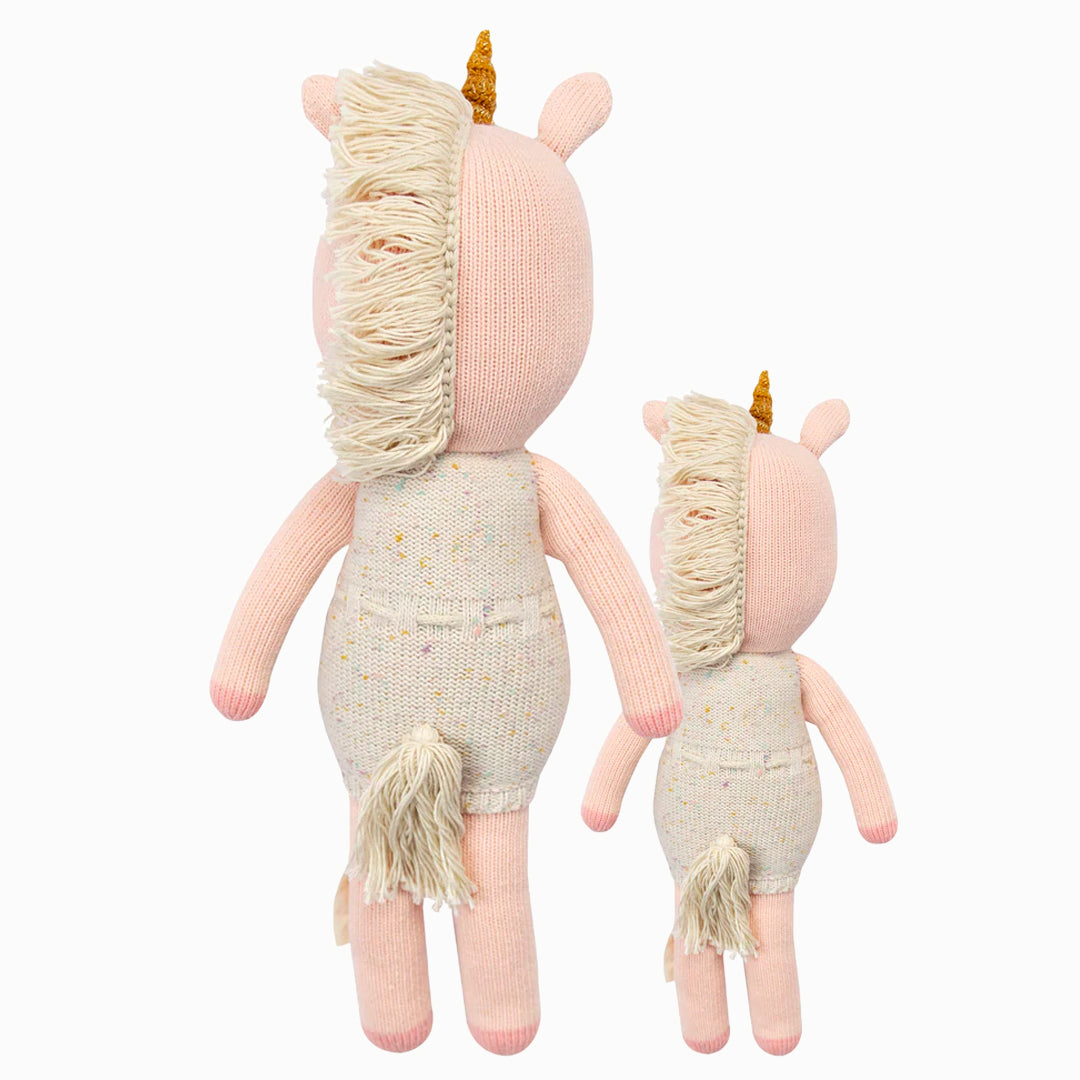 Cuddle and kind doll Ella the unicorn in the regular and little sizes, shown from the back. Ella has a tasselled mane and tail.