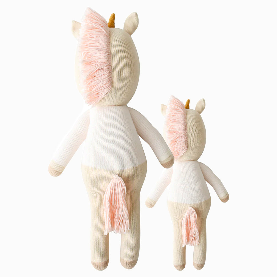 Cuddle and kind doll Zara the unicorn in the regular and little sizes, shown from the back. Zara has a pink tasselled mane and tail.