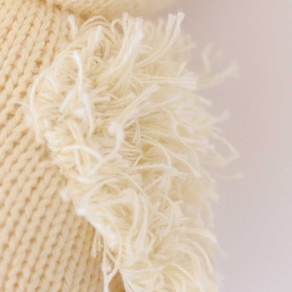 A close up showing the hand-knit details on baby duckling, including its fluffy yarn wing.