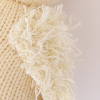 A close up showing the hand-knit details on baby duckling, including its fluffy yarn wing.