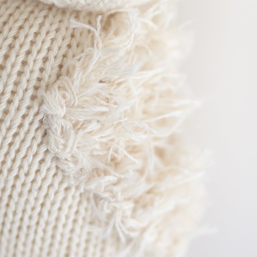 A close up showing the hand-knit details on baby gosling, including its fluffy yarn wing.