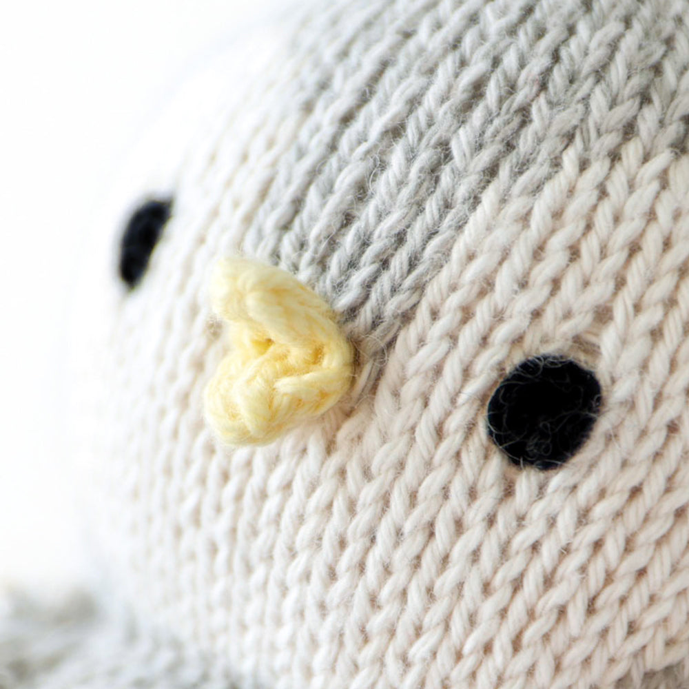 A close up showing the hand-knit details on baby penguin, including its teensy yellow beak.