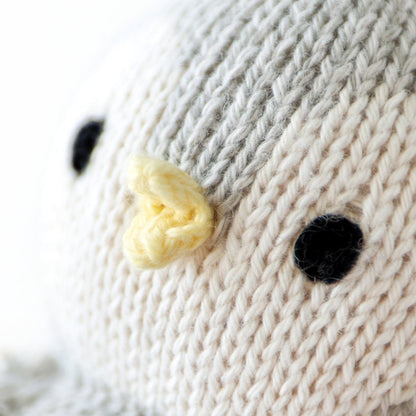 A close up showing the hand-knit details on baby penguin, including its teensy yellow beak.