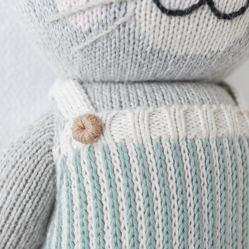 A close-up showing hand-knit details on Dylan the kitten, including a knitted button.