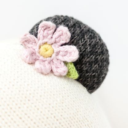 A close-up showing the hand-knit detail of the flower on Polly the panda’s ear.