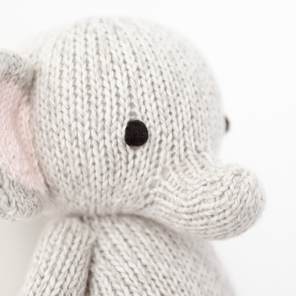 A close up showing the hand-knit details on baby elephant, including its hand-knit ears and trunk.