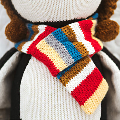 A close-up showing a knitted scarf on an Everest the penguin doll.