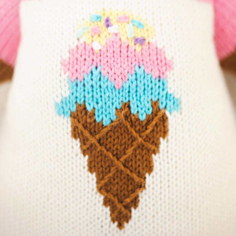 A close-up showing hand-knit details on Willow the deer, including an ice cream cone design on her romper.