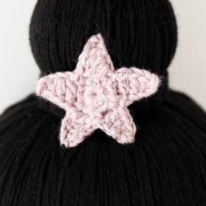 A close-up showing a hand-knitted star on top of Luna’s bun.