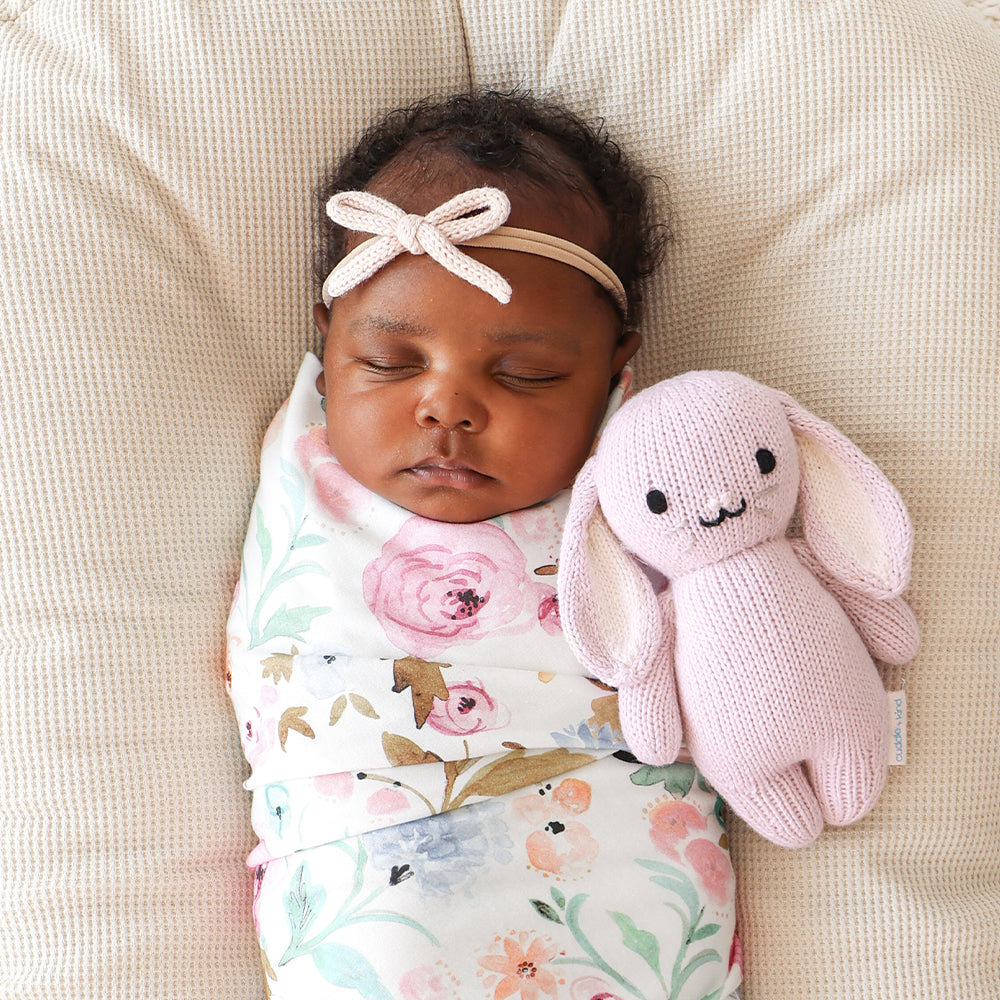 A sleeping baby snuggled next to a baby in lilac.