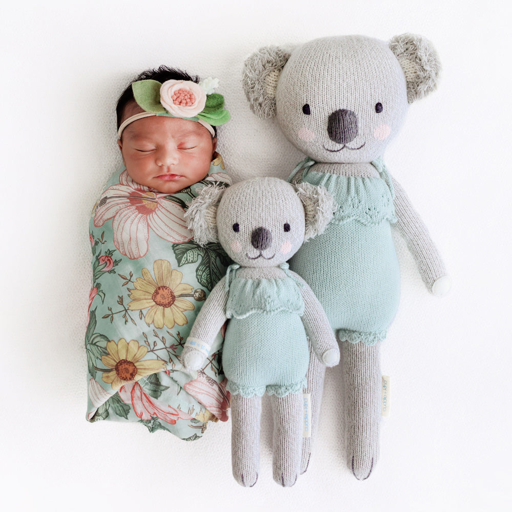 A sleeping baby with two Claire the koala dolls in the little and regular sizes.