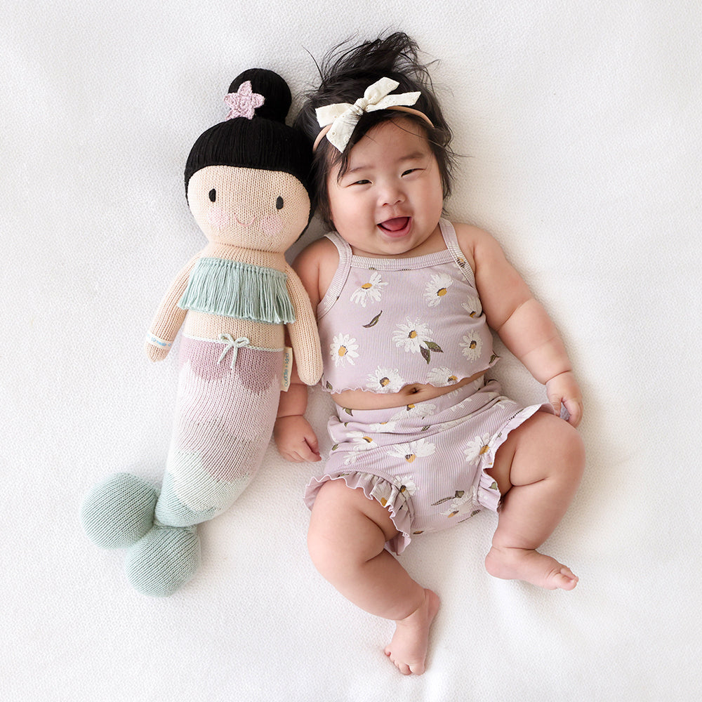 A laughing baby with a Luna the mermaid doll.