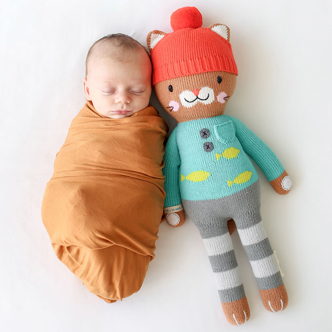 A sleeping baby next to a Maximus the cat doll.