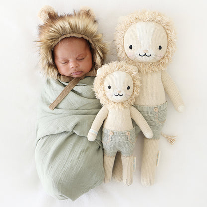 A sleeping baby in a fluffy lion hood with Sawyer the lion dolls in the little and regular sizes.