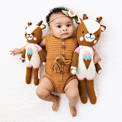 A baby with her arms around Willow the deer dolls in the little and regular sizes.