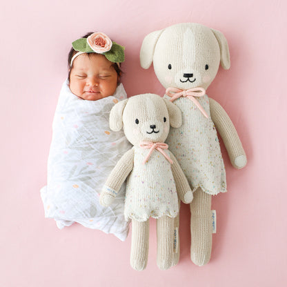 A sleeping baby lying side-by-side with two Mia the dog dolls in the little and regular sizes.