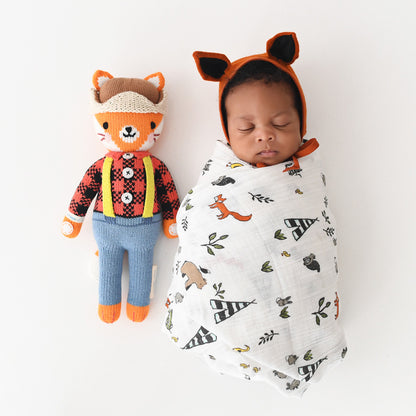 A sleeping baby in a fox hood with a Wyatt the fox doll.