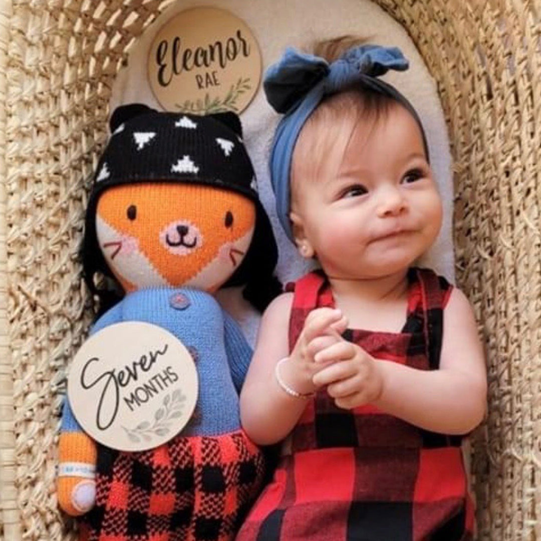 A smiling baby with a Sadie the fox doll.