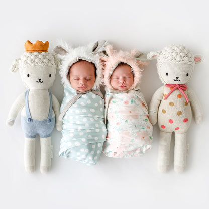 Two sleeping babies snuggled together next to two stuffed lamb dolls: Lucy the lamb and Sebastian the lamb.