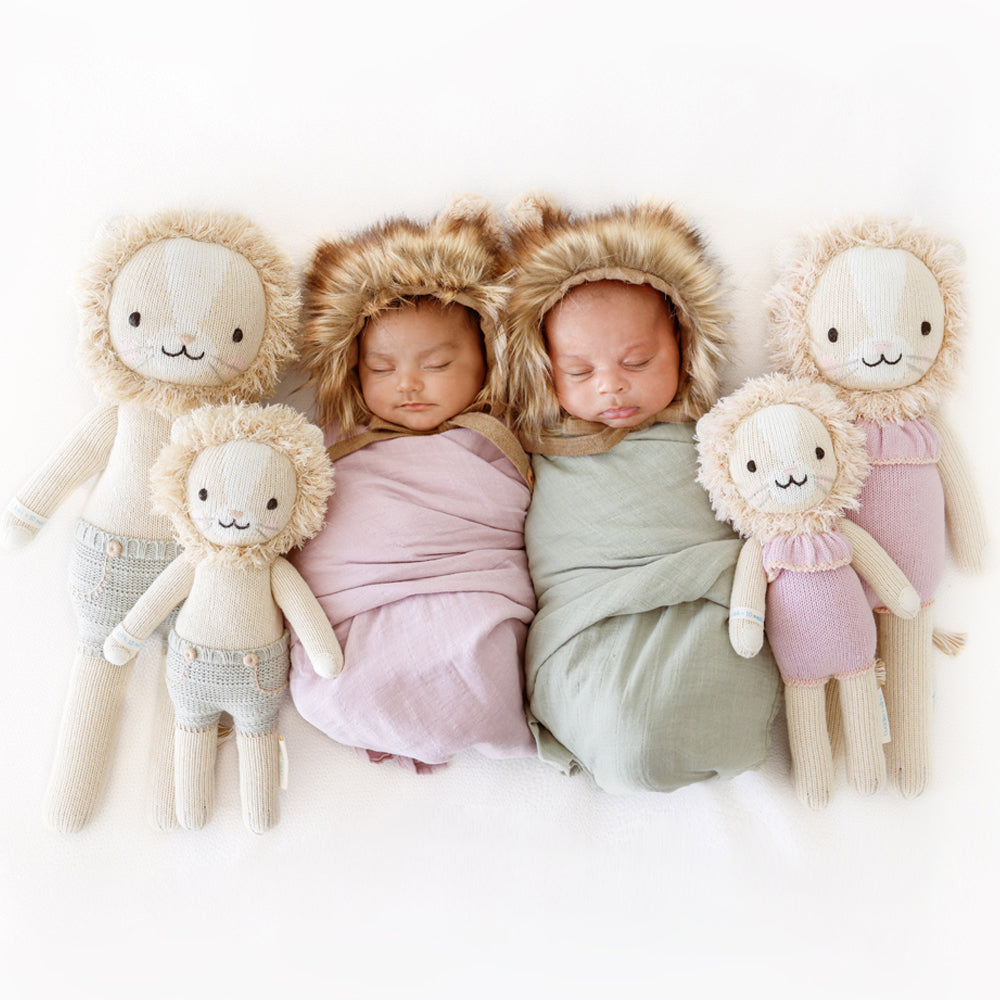 Two sleeping babies snuggled together with four hand-knitted stuffed animals: Sawyer the lion and Savannah the lion in the regular and little sizes.