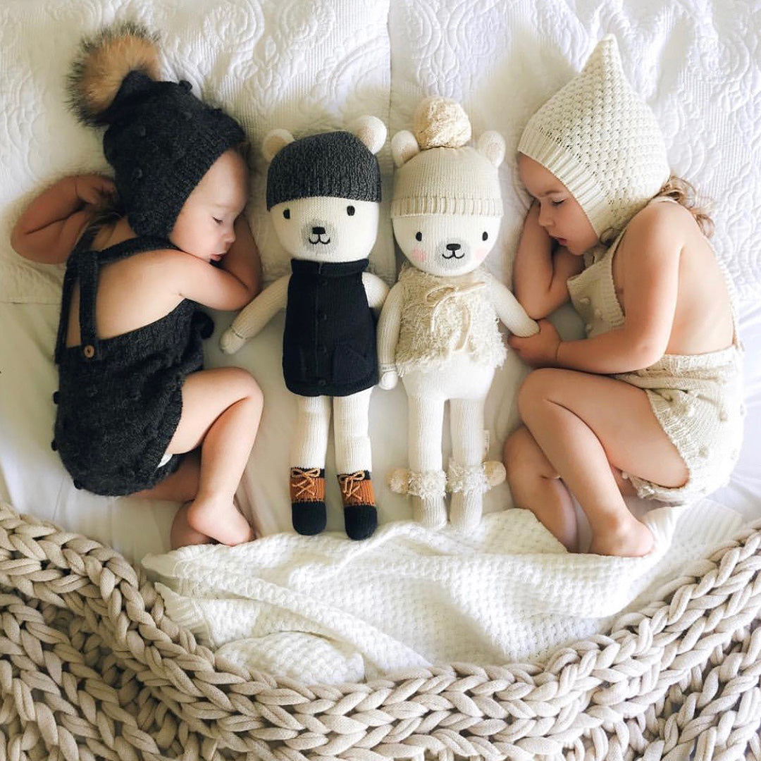 Two sleeping babies snuggled together with Hudson the polar bear and Stella the polar bear dolls.