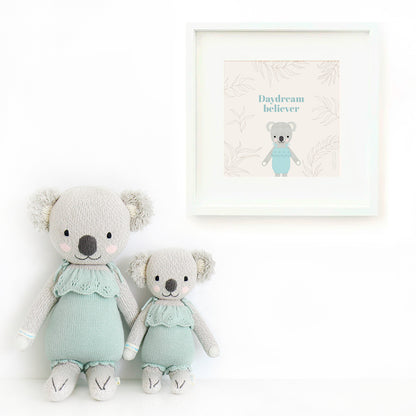 Two Claire the koala stuffed animals sitting beside a framed print with a picture of Claire that says “Daydream believer.”