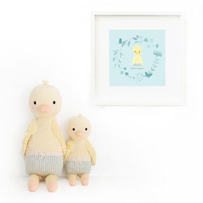 Two Finley the duckling stuffed dolls sitting beside a framed print with a drawing of Finley, with text that says “Better together.