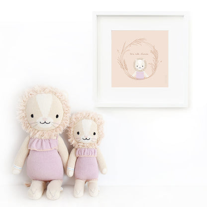 Two Savannah the lion stuffed animals sitting beside a framed print with a picture of Savannah that says “Let’s take chances.”