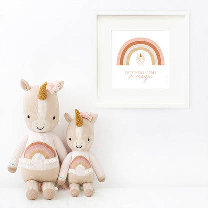 Two Zara the unicorn stuffed animals sitting beside a framed print with a picture of Zara that says “Everything she does is magic.”