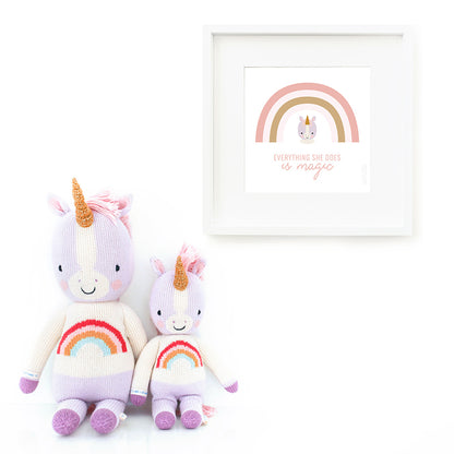 Two Zoe the unicorn stuffed animals sitting beside a framed print with a picture of Zoe that says “Everything she does is magic.”