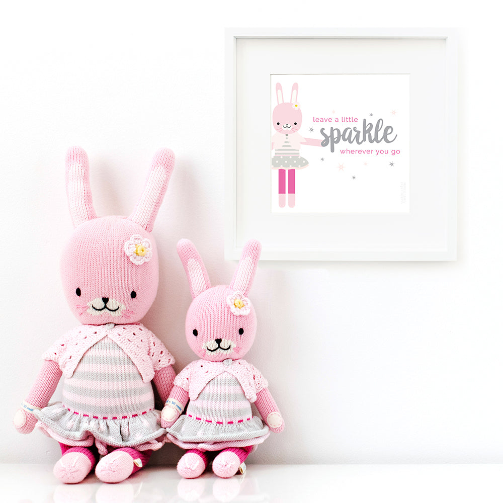 Two Chloe the bunny stuffed dolls sitting beside a framed print with a picture of Chloe that says “Leave a little sparkle wherever you go.”