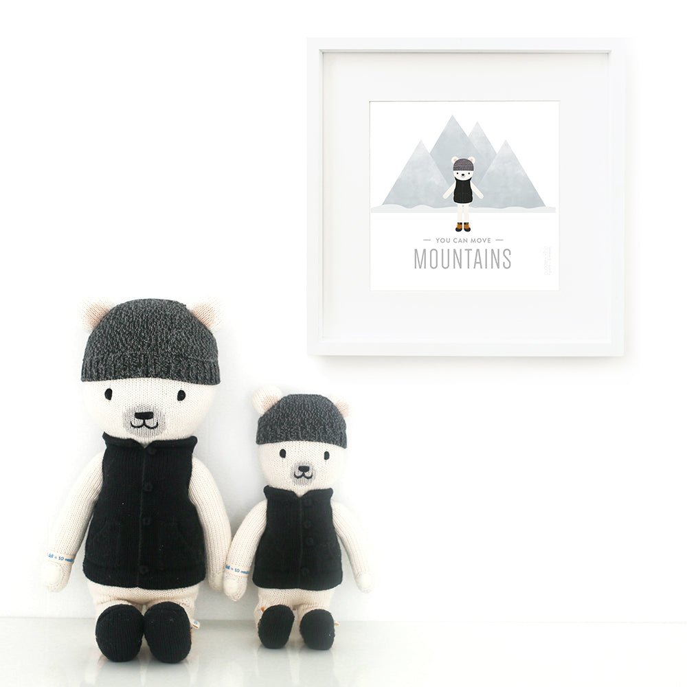 Two Hudson the polar bear stuffed animals sitting beside a framed print with a picture of Hudson that says “You can move mountains.”