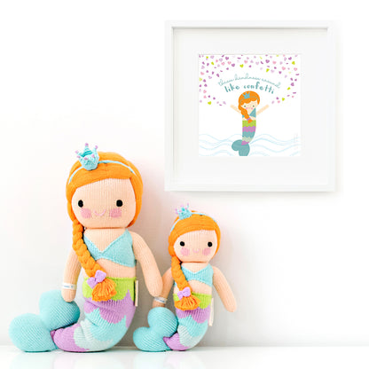 Two Isla the mermaid stuffed animals sitting beside a framed print with a picture of Isla that says “Throw kindness around like confetti.”