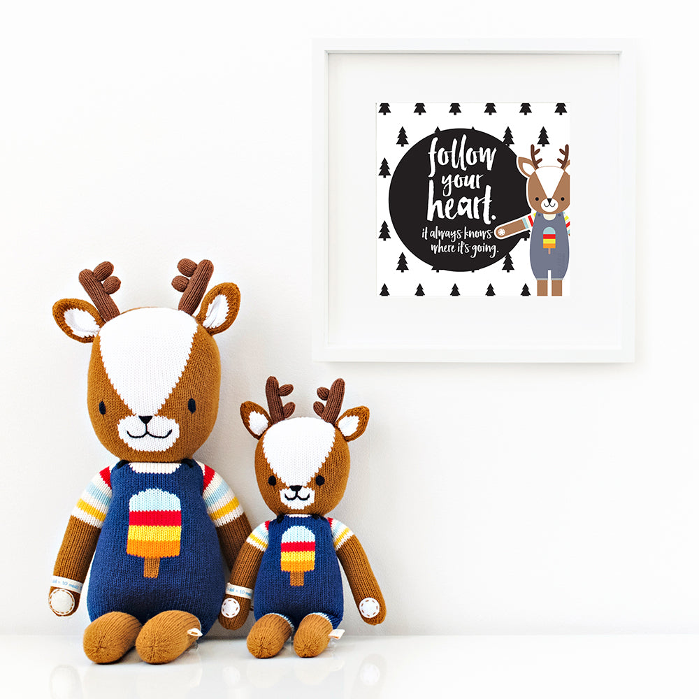 Two Scout the deer stuffed animals sitting beside a framed print with a picture of Scout that says “Follow your heart. It always knows where it’s going.”