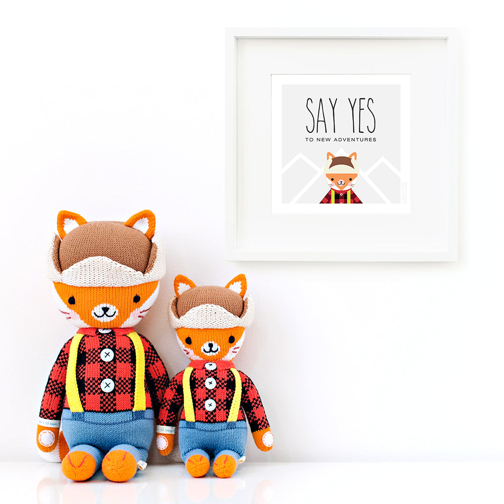 Two Wyatt the fox stuffed animals sitting beside a framed print with a picture of Wyatt that says “Say yes to new adventures.”