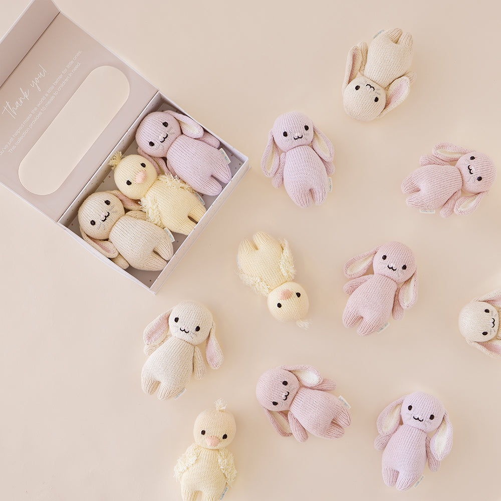 Three baby animals in a baby animal collector’s kit box, next to ten other baby animal dolls. The box has text on it that says “Thank you! You’ve just helped make the world a little better for little ones. This collection provides 15 meals to children in need.”