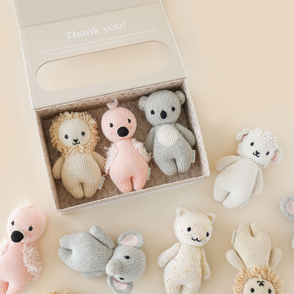 Three baby animals in a baby animal collector’s kit box, next to five other baby animal dolls. The box has text on it that says “Thank you! You’ve just helped make the world a little better for little ones. This collection provides 15 meals to children in need.”