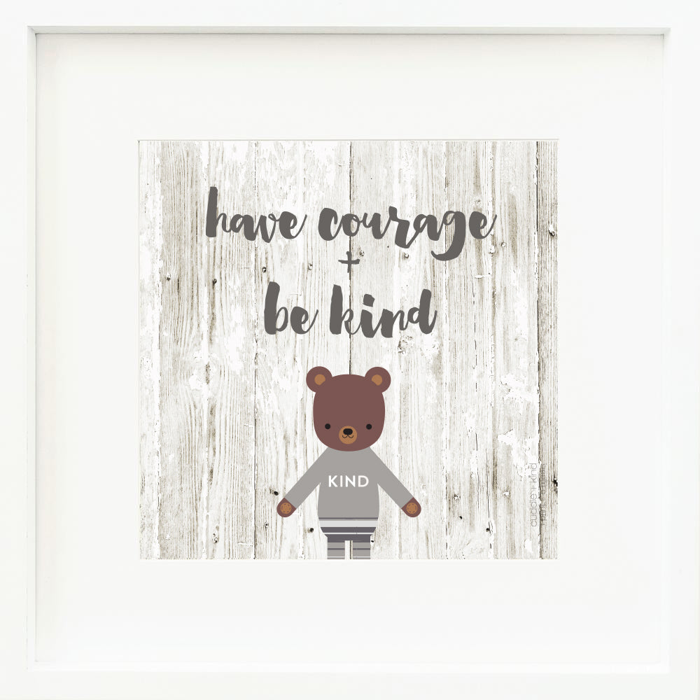 A framed print with a drawing of Oliver the bear and text that says “Have courage + be kind.”